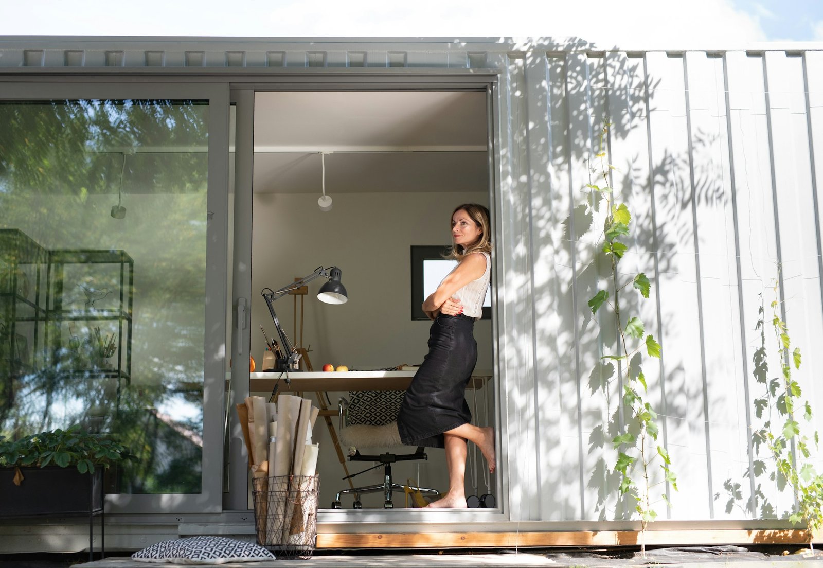 Mature woman working in home office in container house in backyard, resting